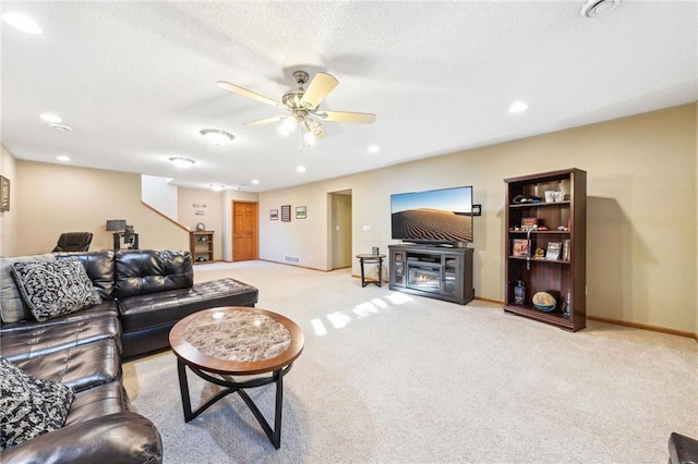 living room featuring ceiling fan, light carpet, and a textured ceiling