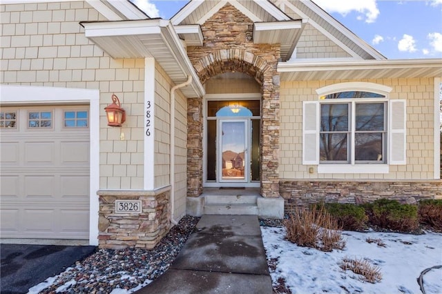 snow covered property entrance with a garage