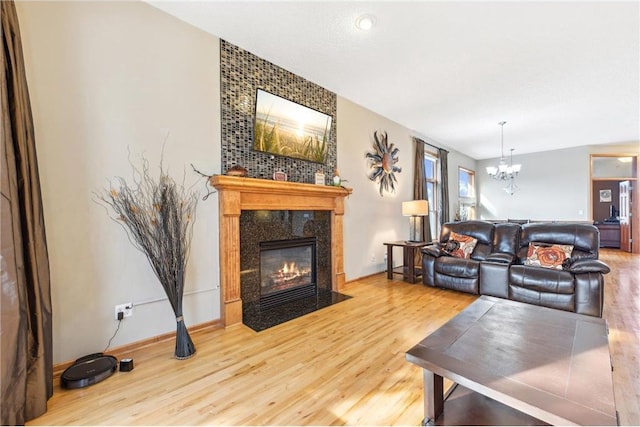 living room featuring wood-type flooring, an inviting chandelier, and a high end fireplace