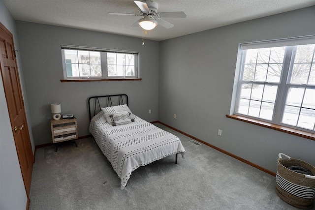 carpeted bedroom featuring multiple windows, ceiling fan, and a textured ceiling