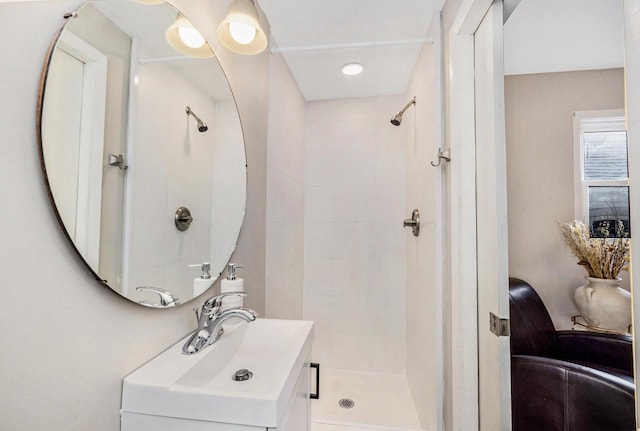 bathroom with tiled shower and vanity