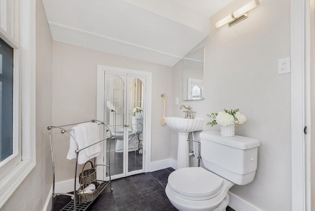 bathroom featuring lofted ceiling, toilet, and sink