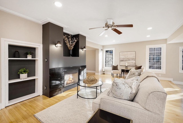 living room with crown molding, ceiling fan, light hardwood / wood-style floors, and built in shelves