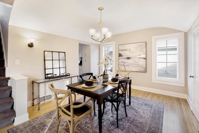 dining room with hardwood / wood-style floors, a notable chandelier, and vaulted ceiling