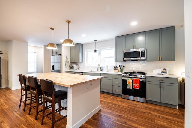 kitchen featuring a kitchen island, gray cabinets, a kitchen bar, and appliances with stainless steel finishes