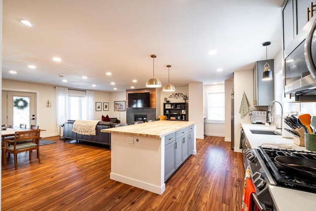 kitchen with a kitchen island, wood counters, pendant lighting, and appliances with stainless steel finishes