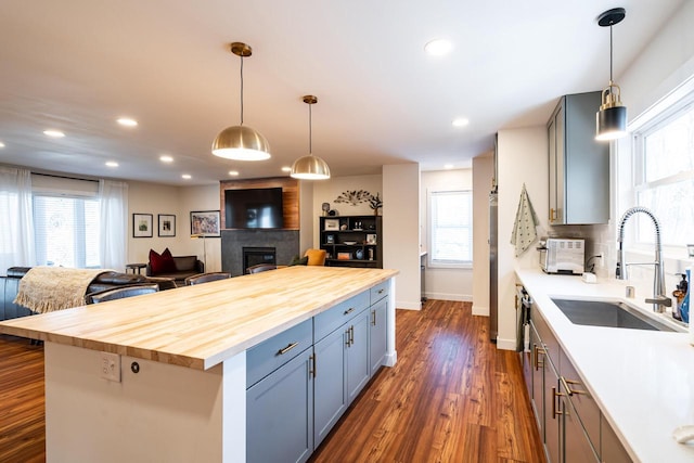 kitchen featuring sink, pendant lighting, butcher block counters, and a fireplace