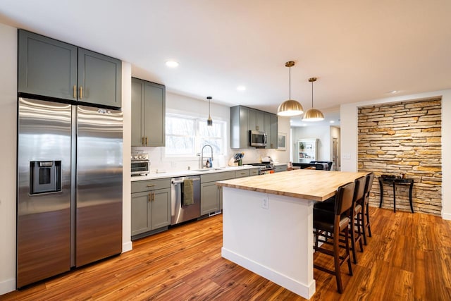 kitchen featuring stainless steel appliances, wood counters, gray cabinets, and a breakfast bar