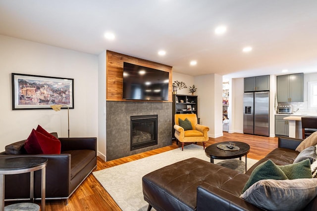 living room featuring light wood-type flooring and a tiled fireplace