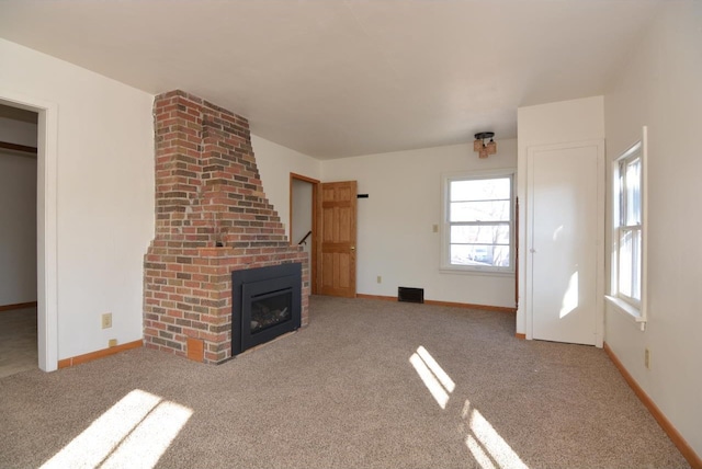 unfurnished living room with a brick fireplace and light colored carpet