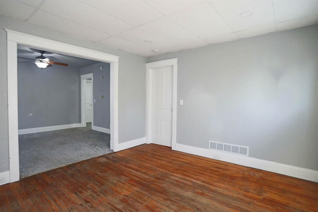 unfurnished room featuring ceiling fan, dark hardwood / wood-style floors, and a paneled ceiling