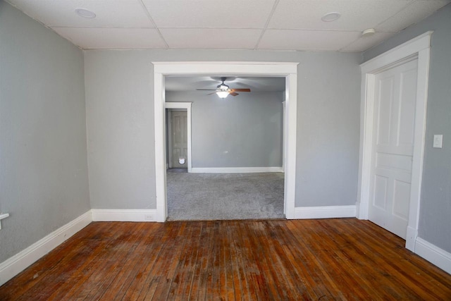 empty room featuring a paneled ceiling, dark hardwood / wood-style floors, and ceiling fan