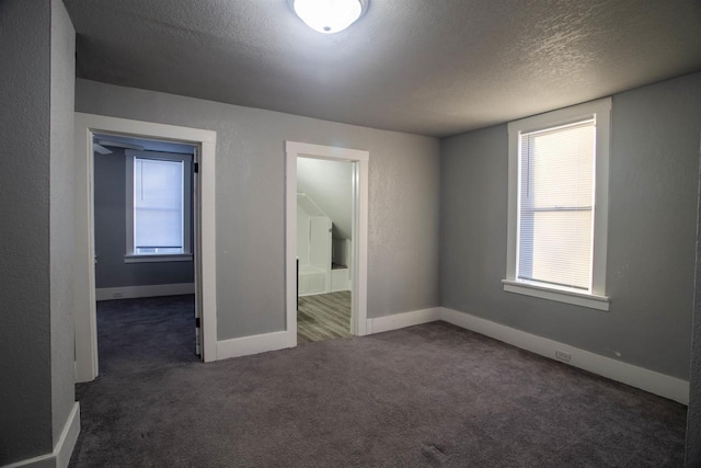 carpeted spare room featuring a wealth of natural light and a textured ceiling