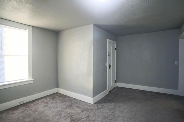 interior space featuring dark colored carpet and a textured ceiling