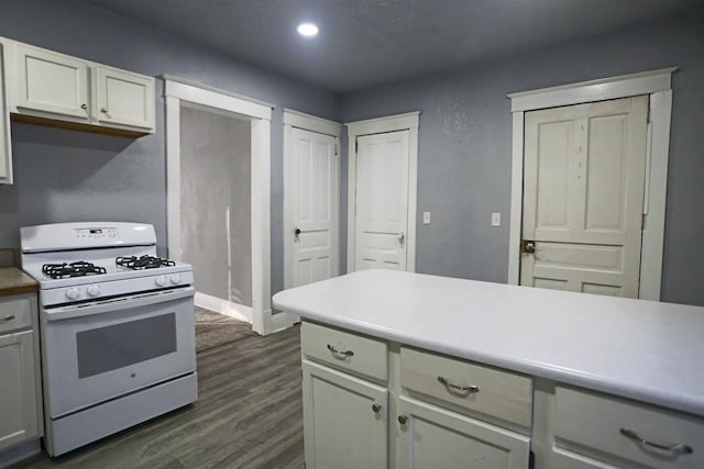 kitchen with white range with gas stovetop, white cabinetry, and dark hardwood / wood-style flooring