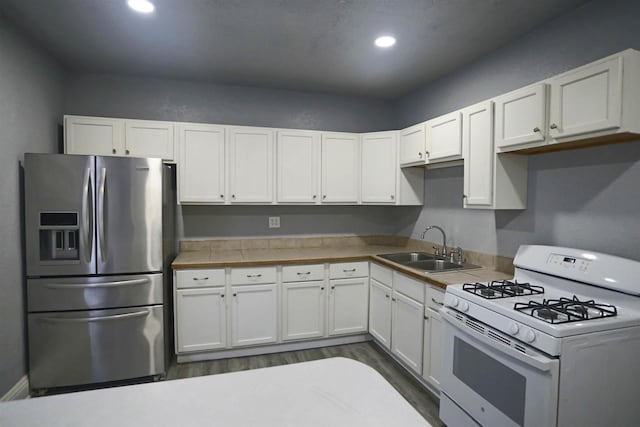 kitchen with stainless steel refrigerator with ice dispenser, sink, dark wood-type flooring, white cabinetry, and white range with gas cooktop