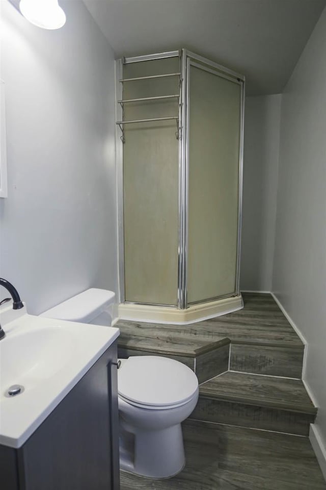 bathroom featuring wood-type flooring, an enclosed shower, vanity, and toilet