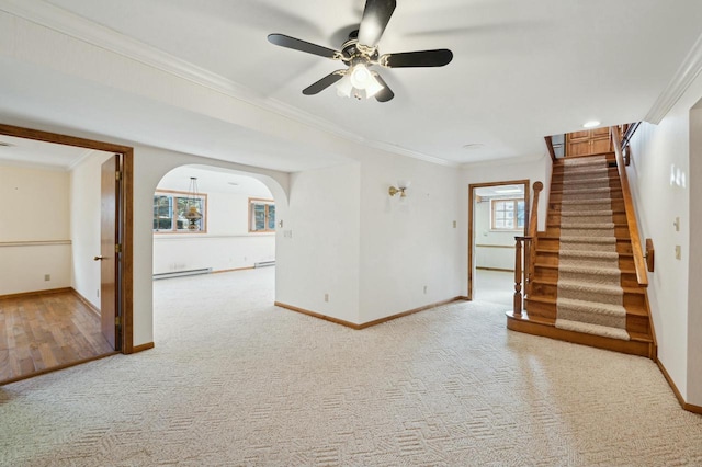 unfurnished living room featuring baseboard heating, ceiling fan, ornamental molding, and carpet floors