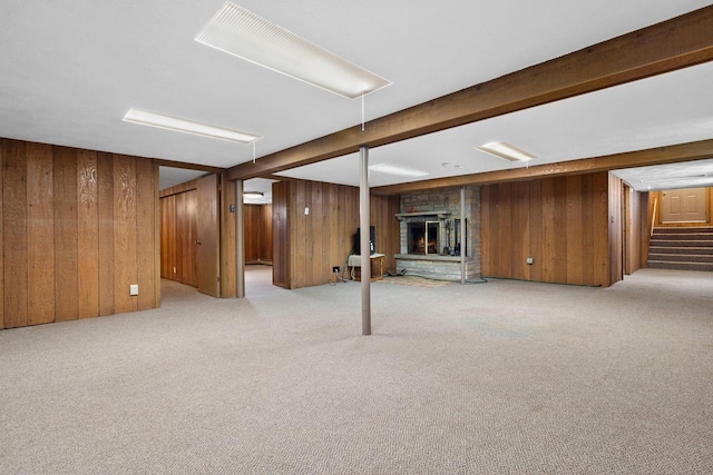 basement with a stone fireplace, light colored carpet, and wooden walls