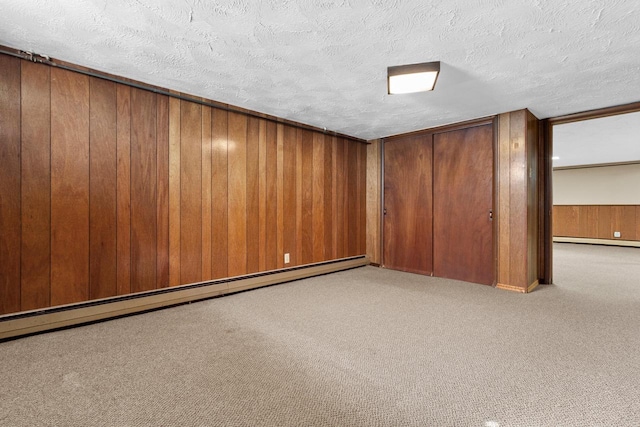 basement with wood walls, a baseboard radiator, a textured ceiling, and light carpet