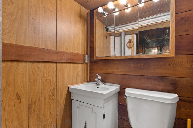 bathroom featuring vanity, toilet, and wood walls