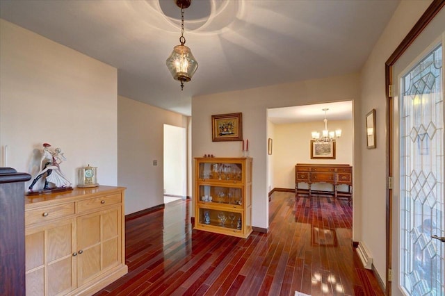 foyer with dark wood-type flooring and an inviting chandelier