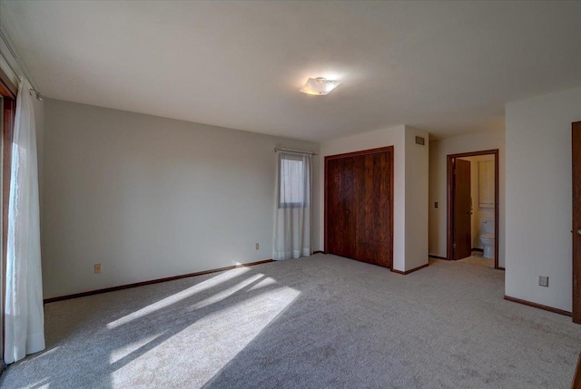 unfurnished bedroom featuring connected bathroom and light colored carpet