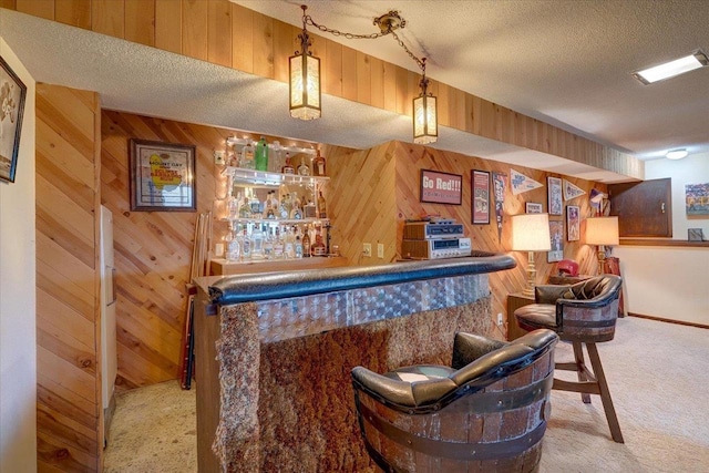 bar featuring hanging light fixtures, carpet floors, a textured ceiling, and wooden walls