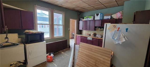 kitchen featuring radiator heating unit, stainless steel fridge, independent washer and dryer, concrete flooring, and decorative backsplash