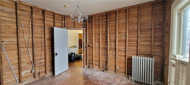 corridor with wood walls, an inviting chandelier, and radiator