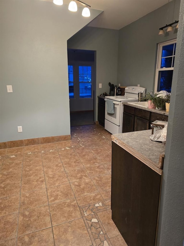 kitchen featuring light tile patterned floors, white range with electric stovetop, and dark brown cabinetry