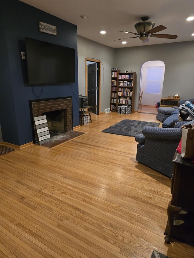 living room with ceiling fan, light hardwood / wood-style flooring, and a fireplace