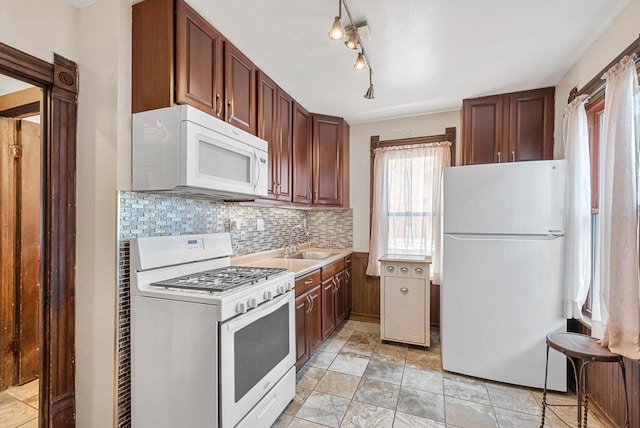 kitchen featuring sink, backsplash, and white appliances