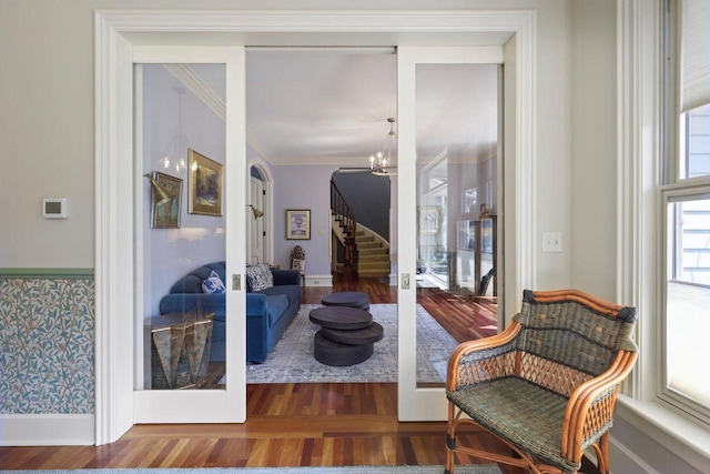 living area featuring a healthy amount of sunlight, crown molding, dark hardwood / wood-style floors, and an inviting chandelier