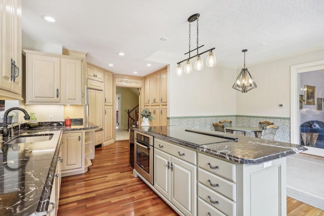 kitchen featuring a kitchen island, decorative light fixtures, sink, oven, and crown molding