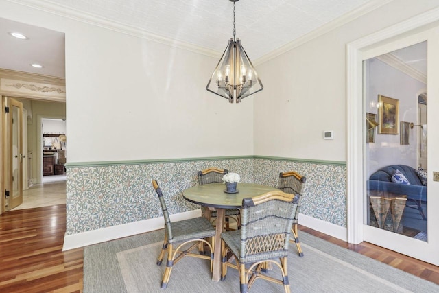 dining room with hardwood / wood-style floors, breakfast area, crown molding, and a chandelier