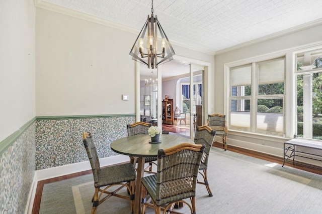 dining area featuring crown molding, hardwood / wood-style flooring, a notable chandelier, and plenty of natural light