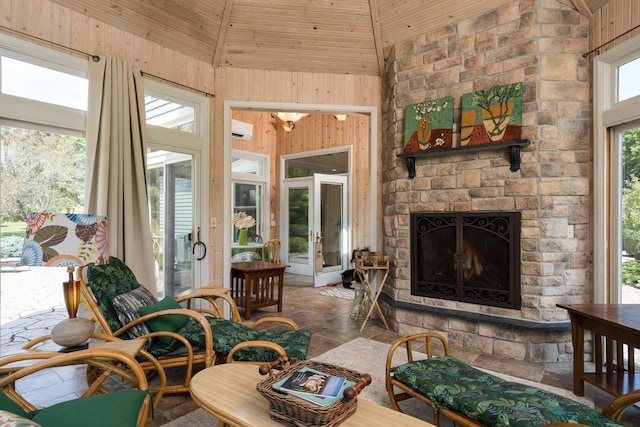 sunroom featuring wooden ceiling, a wall unit AC, a stone fireplace, and vaulted ceiling