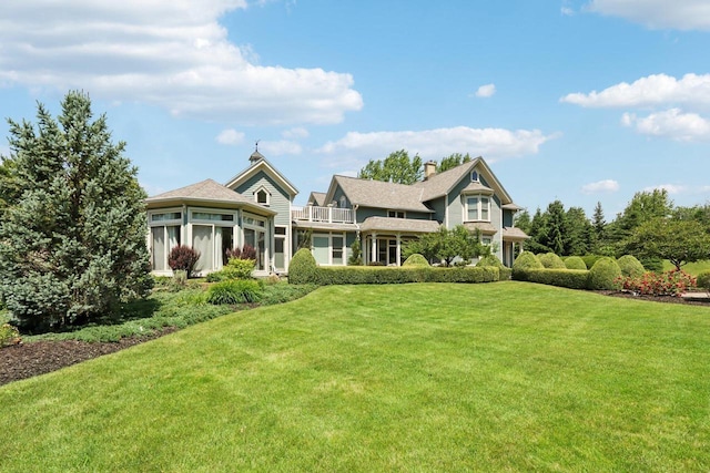 view of front of property featuring a balcony and a front yard