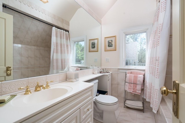 full bathroom featuring lofted ceiling, tile patterned flooring, vanity, tile walls, and toilet