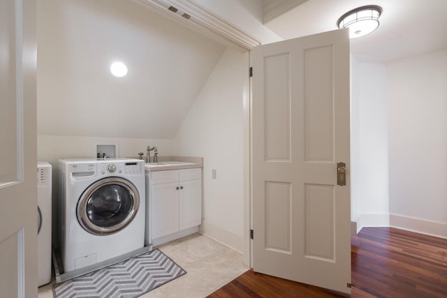 laundry room featuring cabinets, washer and clothes dryer, light hardwood / wood-style flooring, and sink