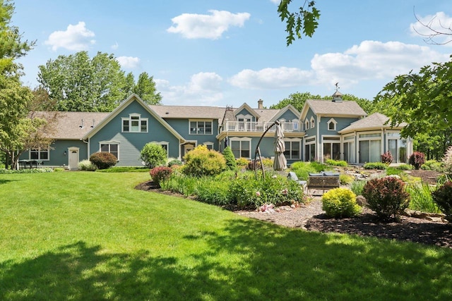 rear view of property with a balcony and a yard