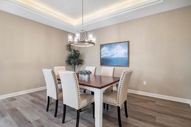 dining room with hardwood / wood-style floors, a raised ceiling, and a chandelier