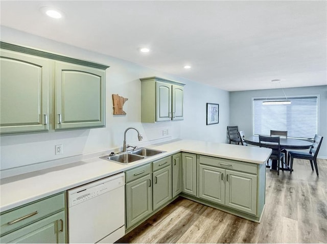 kitchen featuring sink, dishwasher, green cabinetry, kitchen peninsula, and light wood-type flooring