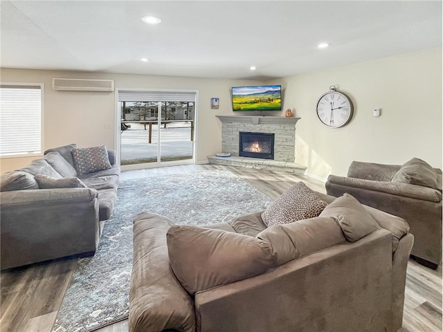 living room with a wall mounted air conditioner, a fireplace, and hardwood / wood-style floors