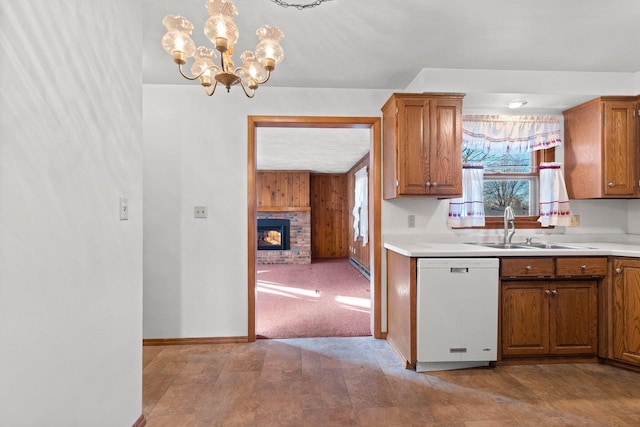 kitchen with light carpet, dishwasher, sink, a fireplace, and a notable chandelier