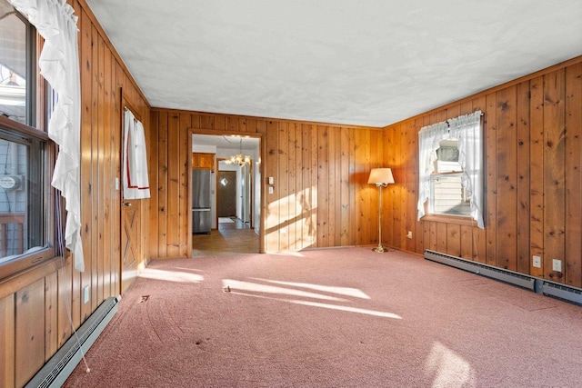 unfurnished room featuring a baseboard radiator, carpet flooring, and a notable chandelier