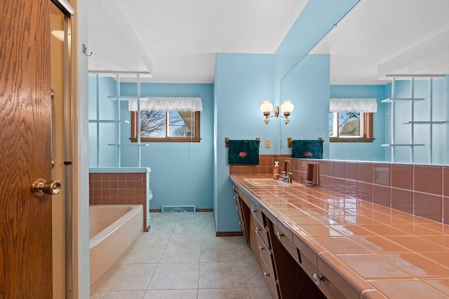 bathroom with tile patterned flooring, vanity, a bath, and a healthy amount of sunlight