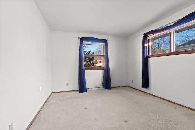 carpeted spare room featuring a baseboard heating unit and a wealth of natural light