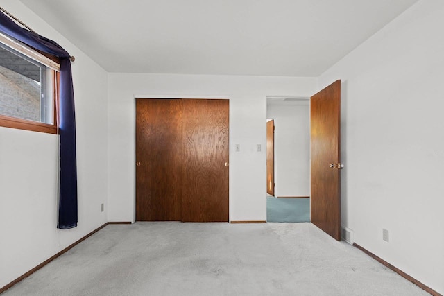 unfurnished bedroom featuring light colored carpet and a closet